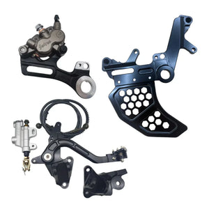 Surron Ultra Bee foot brake kit with OEM caliper laid out on white, black honeycomb bracket, pedal and master cylinder
